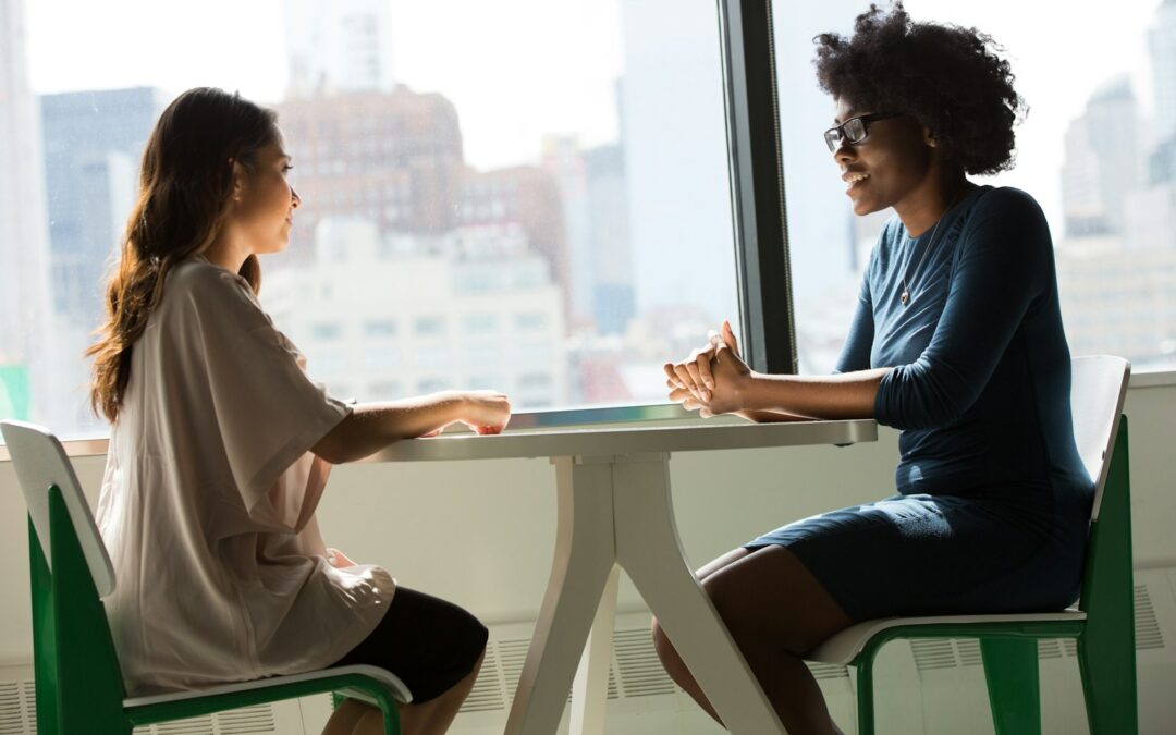 two women sitting beside table and talking